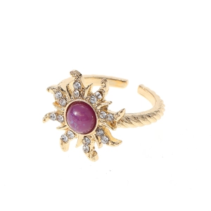 Detailed macro view of an adjustable gold ring with a purple gemstone and starburst rhinestones