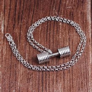 Close-up of a silver dumbbell pendant with an O-chain on a dark wood background