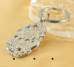 Close-up of silver stainless steel dragon keychain with detailed relief on yellow silk