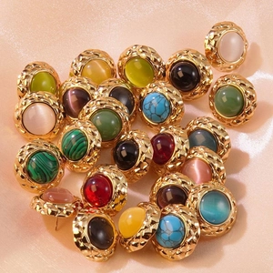 Macro shot of vintage round button earrings with colorful gems on champagne silk