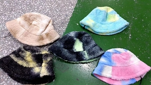 Detailed flat lay of thick faux shearling bucket hats in various tie-dye color patterns