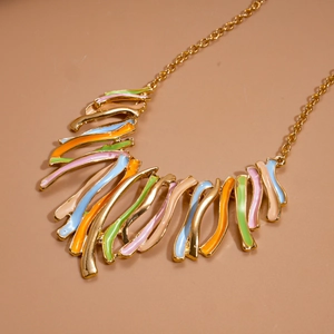 Detailed close-up of colorful enamel geometric fringe pendant with a gold chain finish
