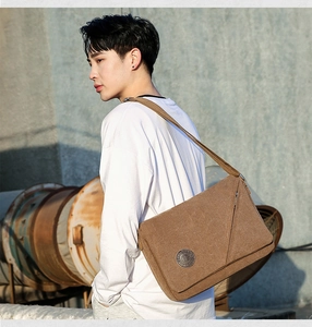 Detailed view of a brown canvas messenger bag with flap cover and adjustable shoulder strap