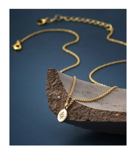 Macro detail of gold oval starburst pendant with white zircon on dark textured rock