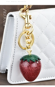 Detailed close-up of a luxury red glitter strawberry charm with gold clasp for handbags