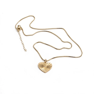 Détail du collier pendentif cœur doré avec texture rayonnante et pierre de zircon centrale