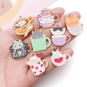 Cat and coffee cup enamel charms in various colors held to show scale and detail