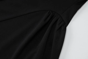 Gros plan d'une robe moulante noire montrant les détails froncés et la texture du tricot