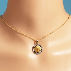 Close-up of titanium steel sun pendant necklace with black enamel detail on model