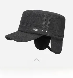 Detail of dark grey wool flat cap featuring foldable earflaps and metal V logo for winter