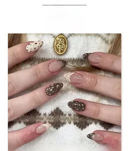 Detailaufnahme brauner French Press-on Nails in Mandelform mit Kuhmuster und 3D-Schleife