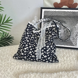 Detail of floral canvas tote bag featuring delicate white lace trim and bow design