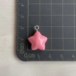Detailed size measurement of pink resin star pendant with ruler on a black cutting mat