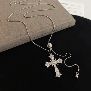Detailed macro view of silver cross pendant with rhinestones and marble bead on chain