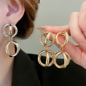 Dettaglio di orecchini geometrici intrecciati in oro e argento su modella e mano