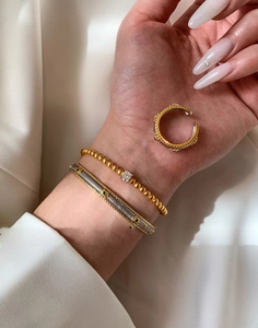 Detail of vintage gold bead bracelet and bicolor woven bangle on a silk background