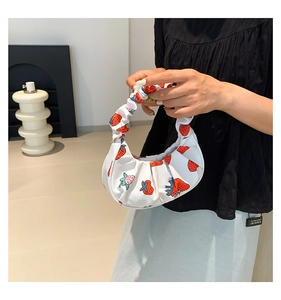 Dettaglio della borsa a mano plissettata bianca con fragole rosse e texture morbida