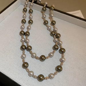 Détail macro du collier double rang avec perles olive et grises dans une boîte à bijoux