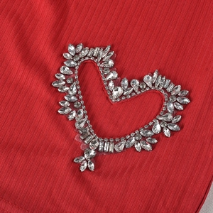 Nahaufnahme der glitzernden Herz-Strass-Dekoration auf rotem Rippenstoff-Outfit