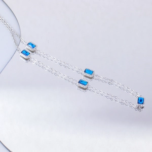 Macro detail of silver steel necklace featuring rectangular blue cubic zirconia stones
