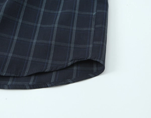 Detailed close-up of dark blue plaid poplin shirt hem with precise double stitching