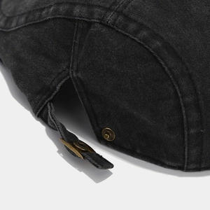 Close-up of adjustable metal buckle and stitching on black washed denim beret cap