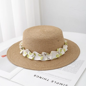 Detail of flat top straw hat with floral ribbon on a white magazine background