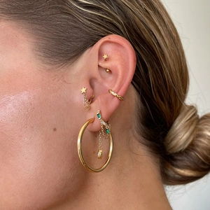 Detail of s925 silver earrings with green zircon pendant and star tassel chain worn on ear