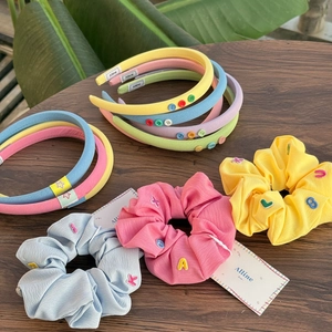 Colorful macaron hair accessories set featuring headbands and scrunchies on wooden table