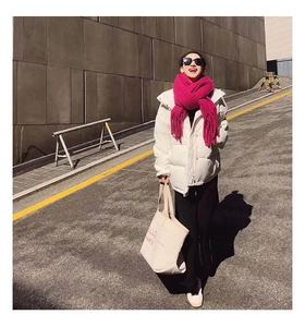 Outdoor look of model wearing warm pink scarf and white down jacket with canvas bag