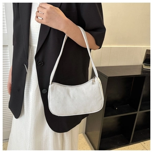 Detailed texture of white corduroy shoulder bag styled on a model in a minimalist setting