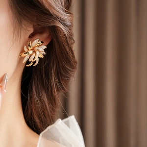 Detail of vintage gold-plated daisy earrings with ivory enamel petals worn by model