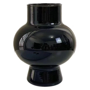 Minimalist spherical black glass flower vase with glossy reflective finish on white background