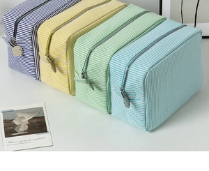 Detailed top view of striped seersucker makeup bags in four vibrant colors with metal zippers