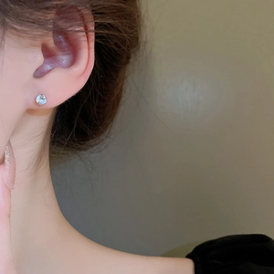 Close-up of a classic silver round cubic zirconia stud earring on a model ear lobe