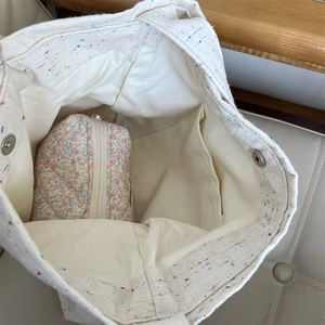 Vista interna della borsa in tela beige con pochette floreale e chiusura magnetica