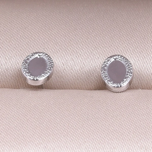 Detailed macro view of silver stainless steel oval stud earrings with textured radial edges