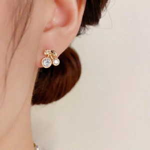 Sweet cherry shaped gold drop earrings with white crystals and leaf detail on ear