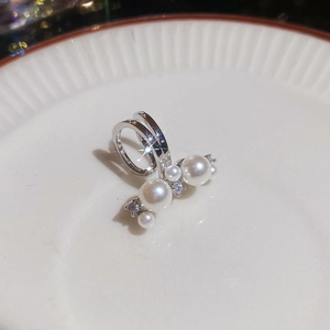 Macro shot of elegant silver clip-on earring with zircons and white pearls on ceramic