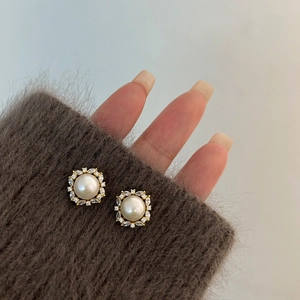 Nahaufnahme der 14K vergoldeten Perlenohrringe mit Zirkonia auf einem weichen Ärmelbund