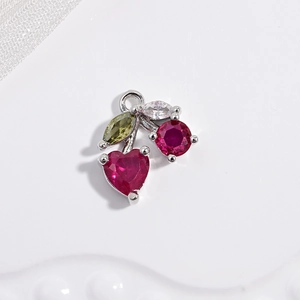 Macro shot of silver cherry pendant with red heart crystals and green leaf stones