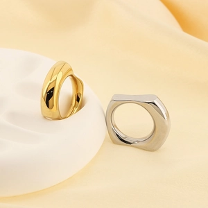 Detail of 18k gold and silver irregular square rings on silk fabric and stone base