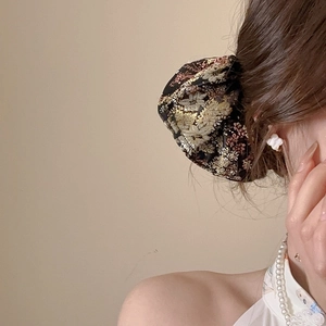 Detail view of retro floral embroidery on premium fabric hair accessory worn by a model