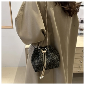 Close-up of leopard print bucket bag featuring gold chain drawstring and pearl accents