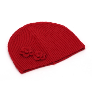 Close-up of red knitted beanie featuring detailed rib-stitch and crochet flower decor
