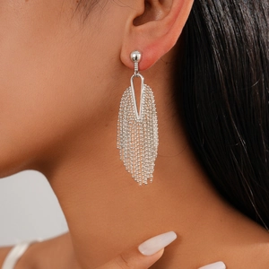 Close-up of silver beaded tassel earrings on model featuring hollow geometric design