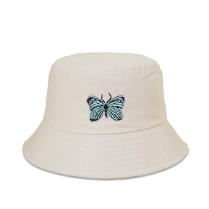 Détail de la broderie papillon bleu sur le chapeau bob en toile de coton beige pour femme