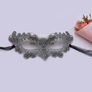 Detail of silver lace masquerade mask with intricate embroidery and black ribbons