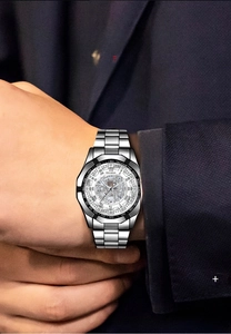 Detailed close-up of a silver stainless steel men's watch with skeleton dial on a navy suit