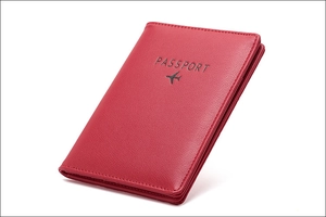 Macro detail of red textured leather passport holder with embossed logo and stitching